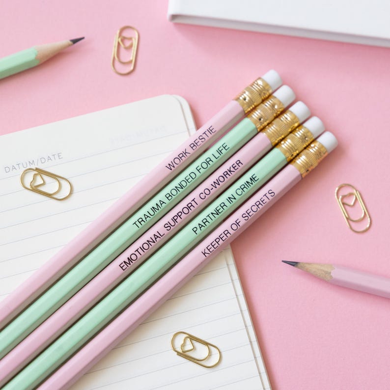 May include: Five pencils with different colored wood and black text on them. The text on the pencils reads "Work bestie", "Trauma bonded for life", "Emotional support co-worker", "Partner in crime", and "Keeper of secrets".