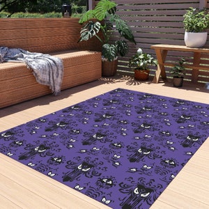 May include: Purple and black patterned rug with a repeating design of a ghost face and a swirling pattern. The rug is laid out on a wooden floor.