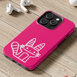 Pode incluir: Uma capa de telefone rosa com um design de gato de desenho animado branco. A capa tem uma protuberância de câmera elevada e um recorte para a porta de carregamento do telefone.