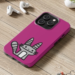 Pode incluir: Uma capa de telefone rosa com um design de gato de desenho animado. A capa tem uma saliência de câmera elevada e um contorno preto ao redor das bordas.