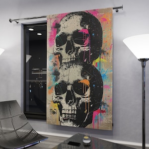 May include: A colorful abstract wall tapestry featuring two black and white skulls with colorful paint splatters. The skulls are stacked on top of each other, with the top skull's eyes covered by sunglasses.