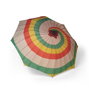 May include: A colorful, open umbrella with a spiral design. The umbrella features alternating stripes of red, yellow, green, and beige. The top of the umbrella has a dark red fabric. The umbrella is designed to provide shade.