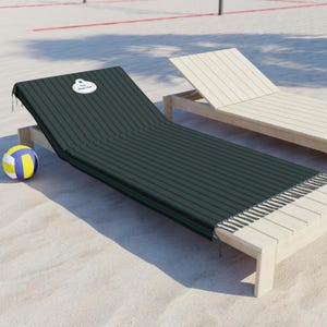 May include: A dark green and black striped beach chair cover with a fringed edge. A volleyball is on the sand next to the chair. The text on the cover says "Your Guest Here".