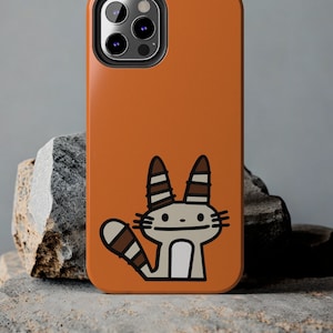 Pode incluir: Capa de telefone laranja com uma ilustração de gato de desenho animado. O gato tem listras marrons e brancas nas orelhas e na cauda.