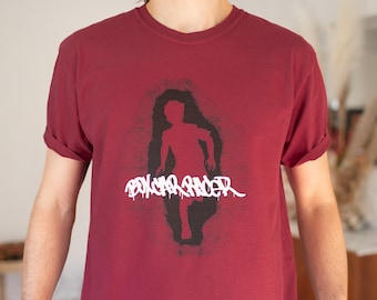 Puede incluir: Una camiseta de color granate con un gráfico en blanco y negro de una figura corriendo y el texto "Boycar Racer".