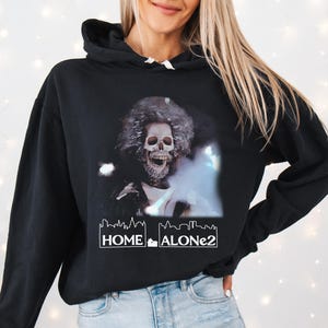 May include: Black hooded sweatshirt with a graphic print of a skeleton wearing a fur-trimmed hat and the text "Home Alone 2".