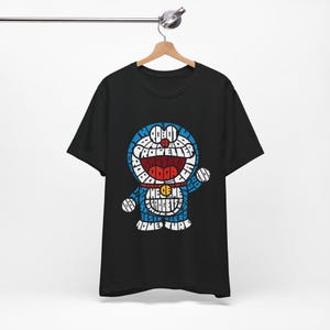 May include: Black t-shirt featuring a blue and white illustration of Doraemon, a popular Japanese cartoon character. The illustration is made up of words related to Doraemon, such as "gadget", "adventure", and "best friend".