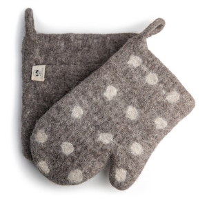 May include: A pair of gray wool oven mitts with white polka dots. The mitts are made of felted wool and have a loop handle. The mitts are labeled "Arctic Collection".