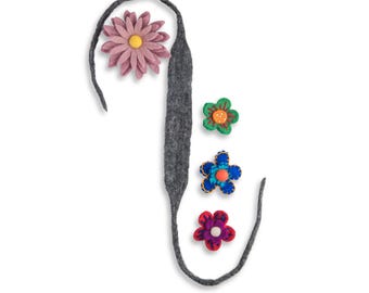 May include: A gray felt ribbon shaped like the letter J with four felt flowers attached to it. The flowers are pink, green, blue, and red.