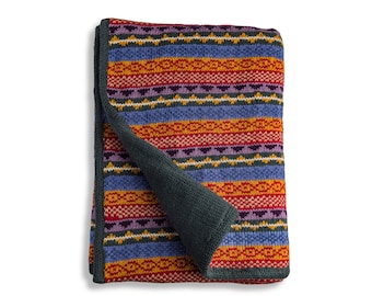 May include: A colorful striped throw blanket with a dark green underside. The blanket is folded in half and has a woven pattern.