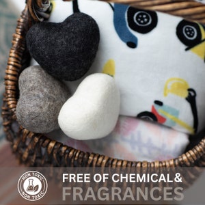 May include: A wicker basket filled with three felt heart-shaped toys in gray, white, and black. The basket also contains a white baby blanket with a colorful print of toy trucks. The label on the basket reads "Non-Toxic". The text "Free of Chemical & Fragrances" is displayed below the basket.