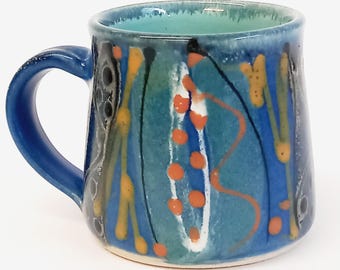 Handmade stoneware ceramic mug, deep blue with vibrant colourful decoration, fresh turquoise glaze inside.