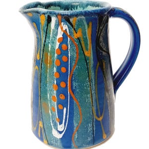 A midnight blue jug is shown on a white background. The primary colour is blue with a turquiose oval and trailed lines in bright orange, yellow, white and black. The handle points to the right.