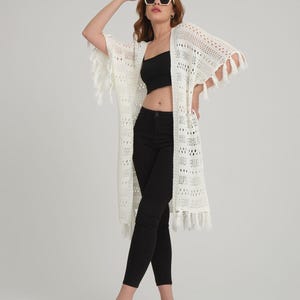 フリンジ付きのレディース用ニットロングカーディガン。美しいジャカード編みのディテール。写真の女性はMサイズで身長172cmです。