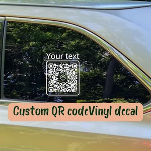 May include: A white vinyl decal applied to a car window, featuring a square QR code with a small fox icon in the center. Above the QR code, the text "Your text" is printed in a simple white font. The decal is designed for vehicle glass application.