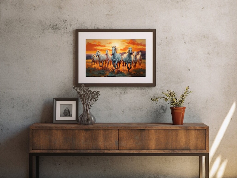 May include: A framed painting of a group of white horses running through a field at sunset. The horses are in a line, with the lead horse facing the viewer. The background is a blurry landscape with a bright orange sunset.