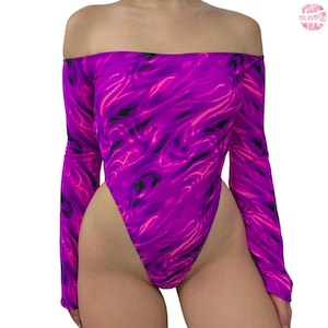 May include: Off-the-shoulder bodysuit in a vibrant purple and pink abstract pattern. The long-sleeved garment features a high-cut leg and a bold, eye-catching design. The bodysuit is made of a stretchy material.