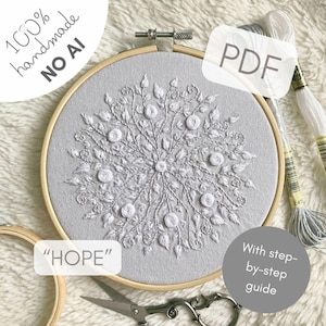 May include: A light gray fabric stretched in a circular wooden embroidery hoop featuring a white floral mandala design with embroidered leaves and circular flower motifs. The text 100% handmade NO AI, PDF, HOPE, and With step-by-step guide are visible.