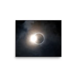 May include: A solar eclipse with the sun's light shining through the moon's silhouette, creating a ring of light. The eclipse is partially obscured by clouds.