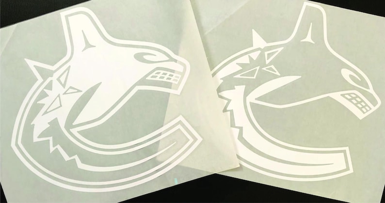 K&ouml;nnte beinhalten: Zwei wei&szlig;e Vinylaufkleber mit dem Logo der Vancouver Canucks. Das Logo ist ein stilisierter Orca-Walkopf, in dessen Design der Teamname integriert ist. Die Aufkleber befinden sich auf einer wei&szlig;en R&uuml;ckseite.