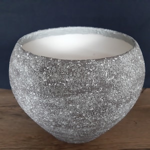 Peut inclure: Un pot en céramique gris avec une surface texturée. Le pot a une large ouverture ronde et un fond légèrement arrondi.