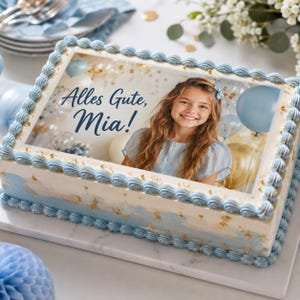 Könnte beinhalten: Ein rechteckiger Blechkuchen mit weißer Glasur, hellblauen Spritzdekor-Rändern und Blattgold-Akzenten. Oben befindet sich ein essbares Bild eines lächelnden Mädchens mit langem braunem Haar, blauen Luftballons und dem dunkelblauen Text Alles Gute, Mia!