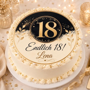 Könnte beinhalten: Ein runder Kuchen mit cremefarbener Glasur, verziert mit weißen und goldenen essbaren Perlen am Rand. Obenauf liegt ein runder Aufleger mit schwarz-goldenem Design, der Zahl 18, dem Text Endlich 18! und dem Namen Lena in Schreibschrift.