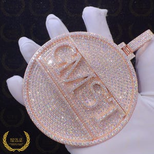 Könnte beinhalten: Ein großer, runder Anhänger aus Roségold mit dem Wort "LOVE" in Diamanten. Der Anhänger ist mit kleinen, funkelnden Diamanten besetzt.