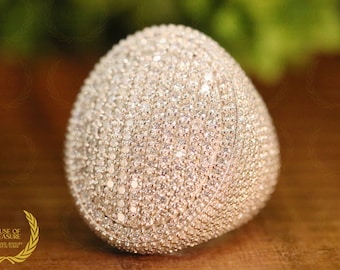 May include: A large, round, silver ring with a textured surface covered in small, white stones.
