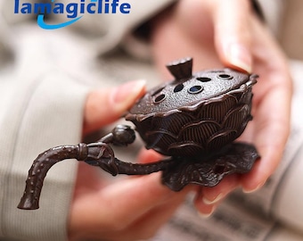 May include: A brown ceramic incense burner shaped like a lotus flower with a handle. The burner has small holes on the top and is sitting on a leaf-shaped base.