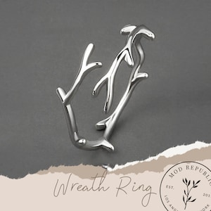 May include: Silver wreath ring with a delicate branch design. The ring is made of metal and has a simple, elegant look.