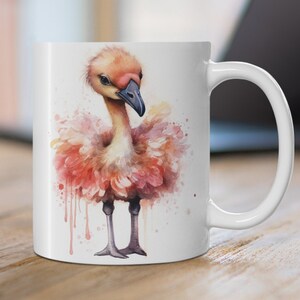 May include: White ceramic mug with a watercolor illustration of a pink flamingo with a long neck and a pink beak. The flamingo is standing on one leg and has its wings spread out.