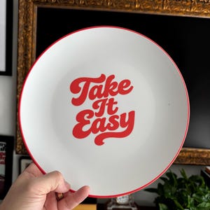 Plato de polímero con arte de pared retro "Tómalo con calma", decoración tipográfica de los años 70, plato con cita vintage en rojo y blanco, decoración de pared con arte retro para cocina. imagen 1