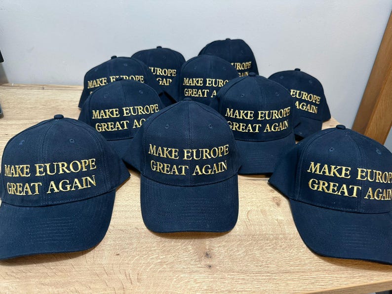Op de afbeelding: Een groep van negen zwarte baseballpetten met gouden borduurwerk. Alle petten hebben dezelfde tekst: "Make Europe Great Again".