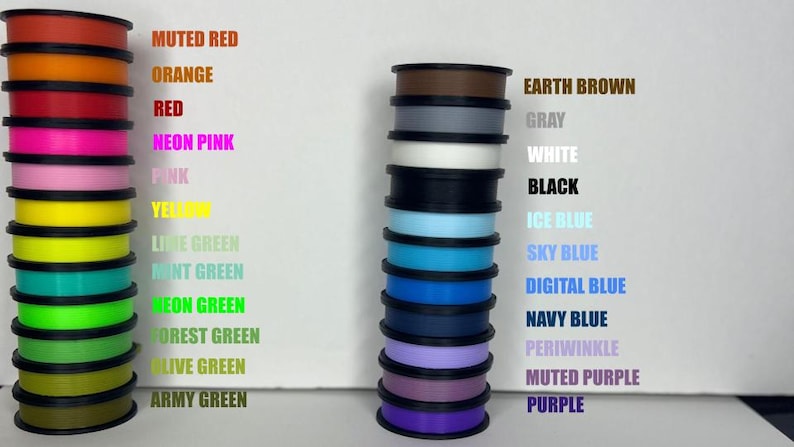 May include: A collection of 18 spools of filament for 3D printing, arranged in two columns. The left column features shades of green, yellow, pink, and red. The right column features shades of blue, purple, brown, gray, and white.