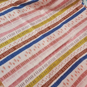 May include: Close-up of a patterned fabric featuring diagonal stripes in pink, yellow, brown, and blue. The stripes are adorned with small floral and leaf motifs. The fabric has a soft, textured appearance, suitable for various textile projects.