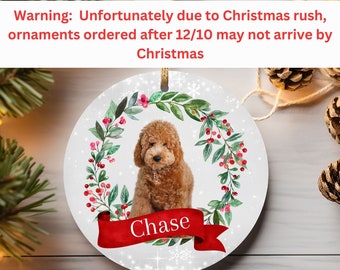 May include: Personalized Christmas ornament featuring a brown dog with a red wreath and berries. The ornament is white with a snowflake pattern and the name "Chase" is written on a red ribbon.