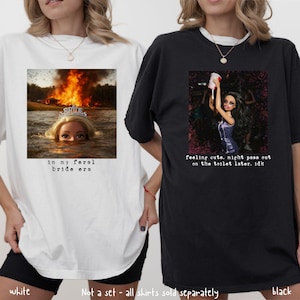 May include: Two oversized t-shirts, one white and one black. The white shirt features a graphic of a doll in water with a burning background and the text "in my feral bride era." The black shirt has a doll graphic and the text "feeling cute, might pass out on the toilet later. idk."