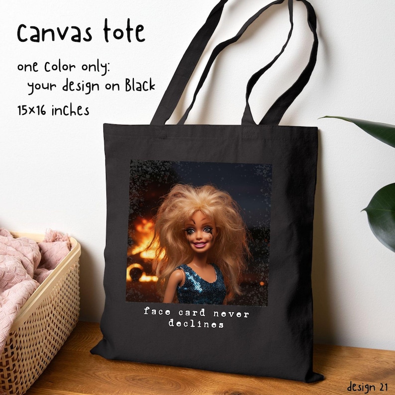 May include: Black canvas tote bag with a doll graphic. The tote bag has black handles and the text "face card never declines". The bag is 15 x 16 inches.