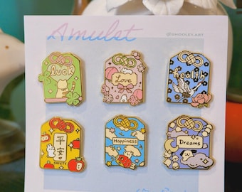 May include: A set of six colorful enamel pins on a white card. Each pin features a unique design with Japanese text and English words like "Luck," "Love," "Health," "Safety," "Happiness," and "Dreams."