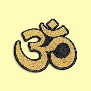 Peut inclure: Un écusson brodé représentant le symbole Om en fil doré métallique avec une bordure noire épaisse. Le motif se compose d'une base incurvée, d'une boucle centrale, d'un croissant supérieur et d'un petit point, le tout en points denses.