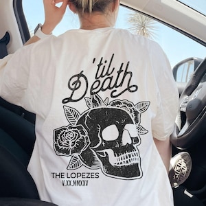 May include: White t-shirt with a black skull and roses graphic. The text 'til Death' is above the skull and 'THE LOPEZES V.XX.MMXXV' is below the skull.