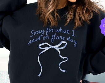 May include: Black sweatshirt with a blue ribbon graphic and the text "Sorry for what I said on flare day". The text "ORIGINAL DESIGNER hot girls don't buy knock-offs" is on a purple circle.
