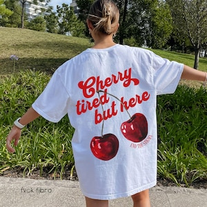 May include: White t-shirt with a red graphic of two cherries and the text "Cherry tired but here" and "End the stigma".