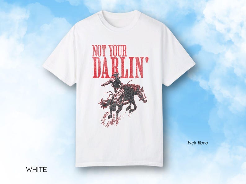 Puede incluir: Camiseta blanca con un gr&aacute;fico rojo de una persona montando a caballo. El gr&aacute;fico dice "Not Your Darlin'" en rojo.