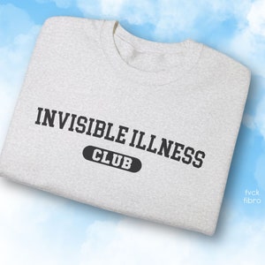 May include: A grey t-shirt with the text "INVISIBLE ILLNESS CLUB" printed in black.