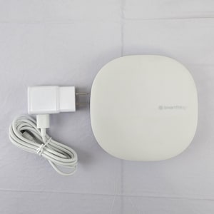 May include: A white SmartThings hub with a matching white power adapter and cable. The hub is a rounded square shape with the SmartThings logo on the lower right. The power adapter has two prongs.