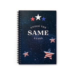 May include: A spiral bound notebook with a dark blue cover featuring a starry night sky design. The cover has three stars in the top center, one white and two red and blue. The text "Under the Same Stars" is printed in white on the cover.