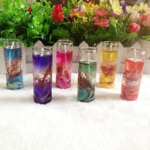 May include: Six clear glass candle holders with colorful gel candles and decorative seashells. The candles are in shades of blue, purple, pink, green, yellow, and red.