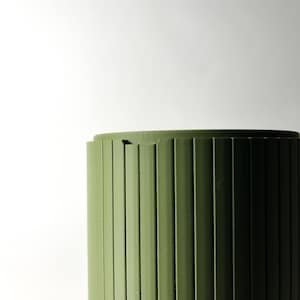 May include: A green cylindrical container with vertical grooves. The container is made of a smooth, plastic-like material.